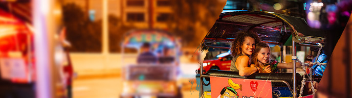 Moeder en kind in een tuktuk tijdens een avondrit in de stad.
