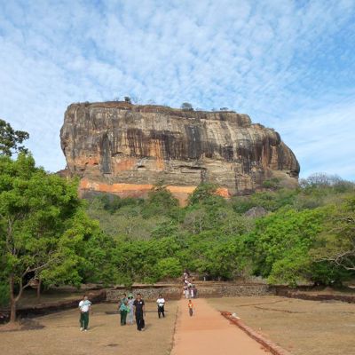 Sigiriya-rots in Sri Lanka, omringd door groen en een wandelpad met bezoekers.