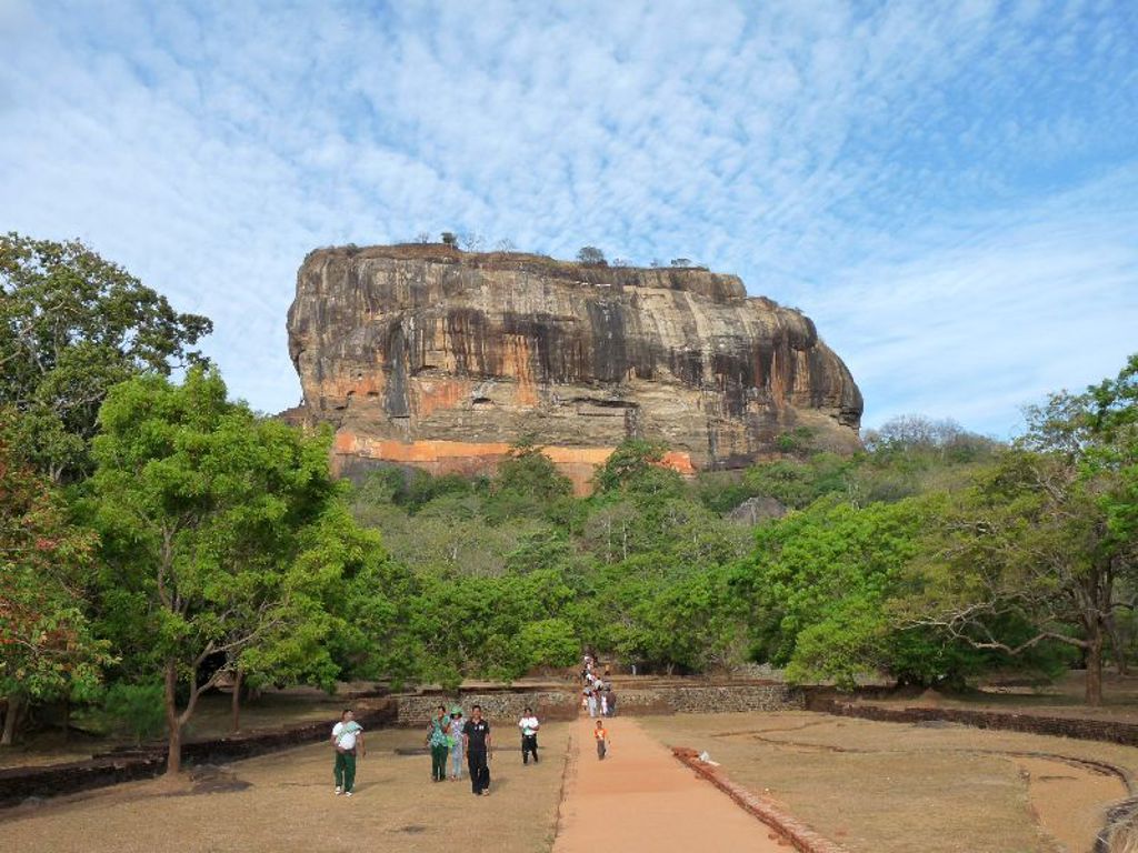 Sigiriya-rots in Sri Lanka, omringd door groen en een wandelpad met bezoekers.