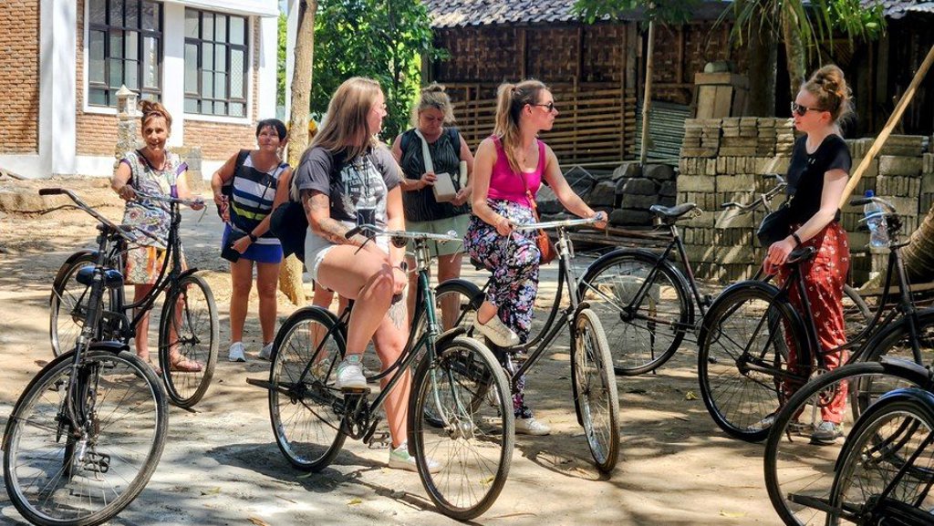 Groepsreizigers in Java en Bali poseren op een terras met uitzicht op rijstvelden.