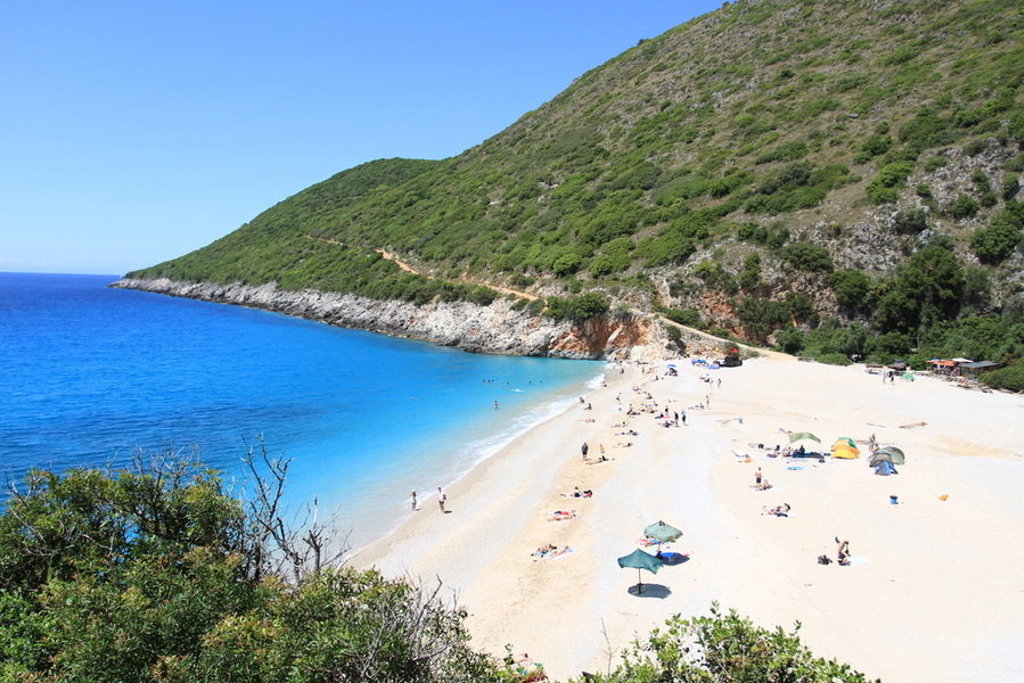 Zandstrand aan de Albanese Rivièra met azuurblauwe zee, ideaal voor een wandelvakantie in Albanië.