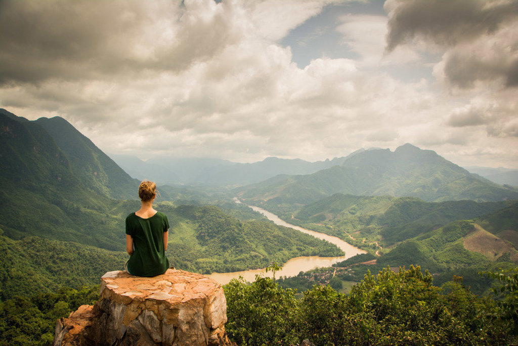 Reiziger op uitzichtpunt met panorama over groene bergen en kronkelende rivier tijdens 22-35ers reis Thailand, Laos & Cambodja.