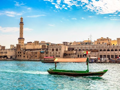Traditionele abra op Dubai Creek met de oude stad en minaret op de achtergrond.