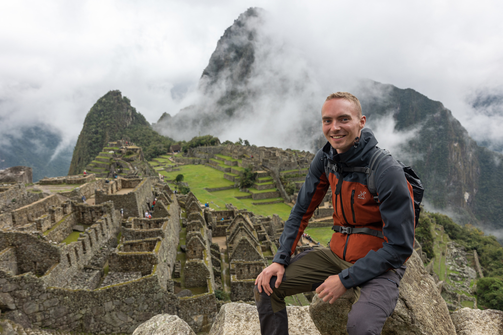 Jonge reiziger bij Machu Picchu tijdens 22-35ers groepsrondreis Peru, met Inca-ruïnes en mistige bergen.