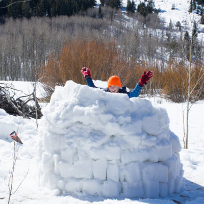 Kind speelt in een sneeuwiglo tijdens familiereis Lapland Winter in Finland.