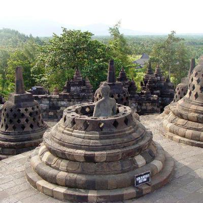 Stupa’s met boeddhabeeld bij Borobudur op Java, met groen landschap op de achtergrond.