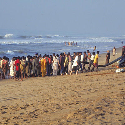 Vissers en omstanders op het strand van Zuid-India trekken samen een groot visnet uit zee.