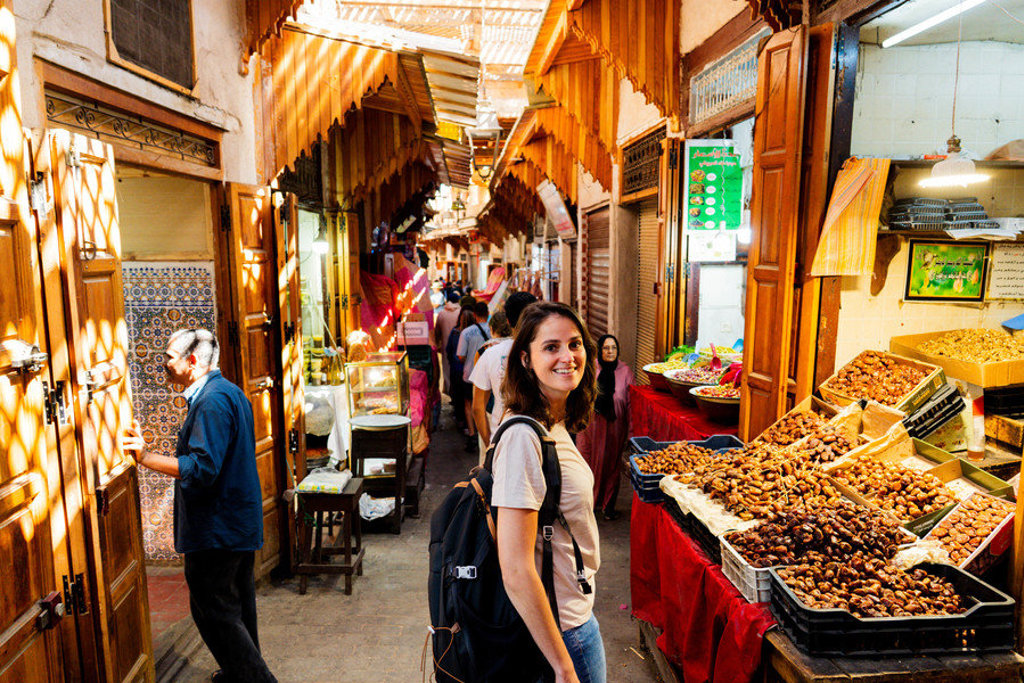 Reiziger in een smalle souk in Marokko met kramen vol dadels tijdens een 22-35ers groepsrondreis.