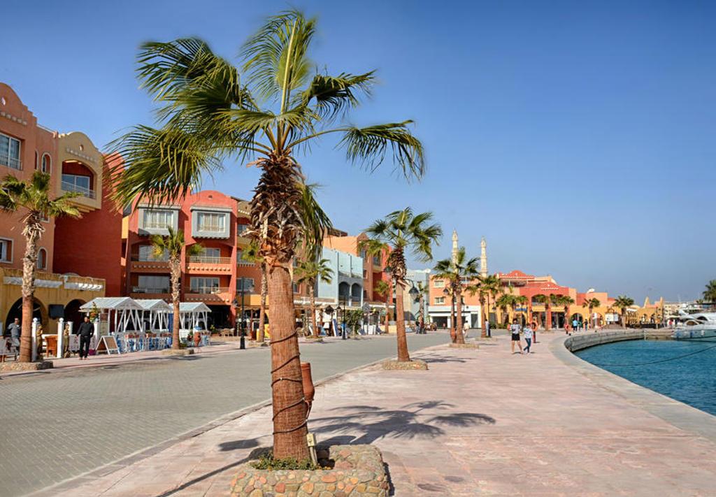 Boulevard met palmbomen en kleurrijke gebouwen aan de jachthaven in Hurghada, Egypte.
