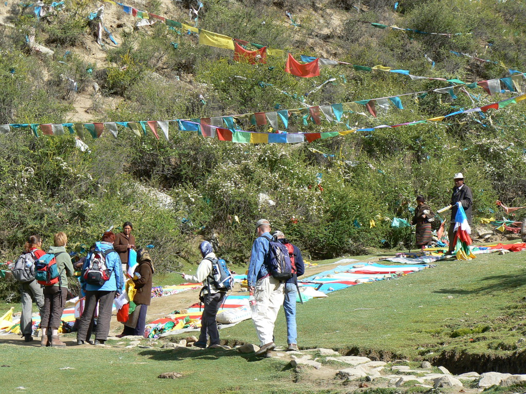 Wandelaars bij Tibetaanse gebedsvlaggen langs een bergpad tijdens groepsrondreis Tibet en Nepal.