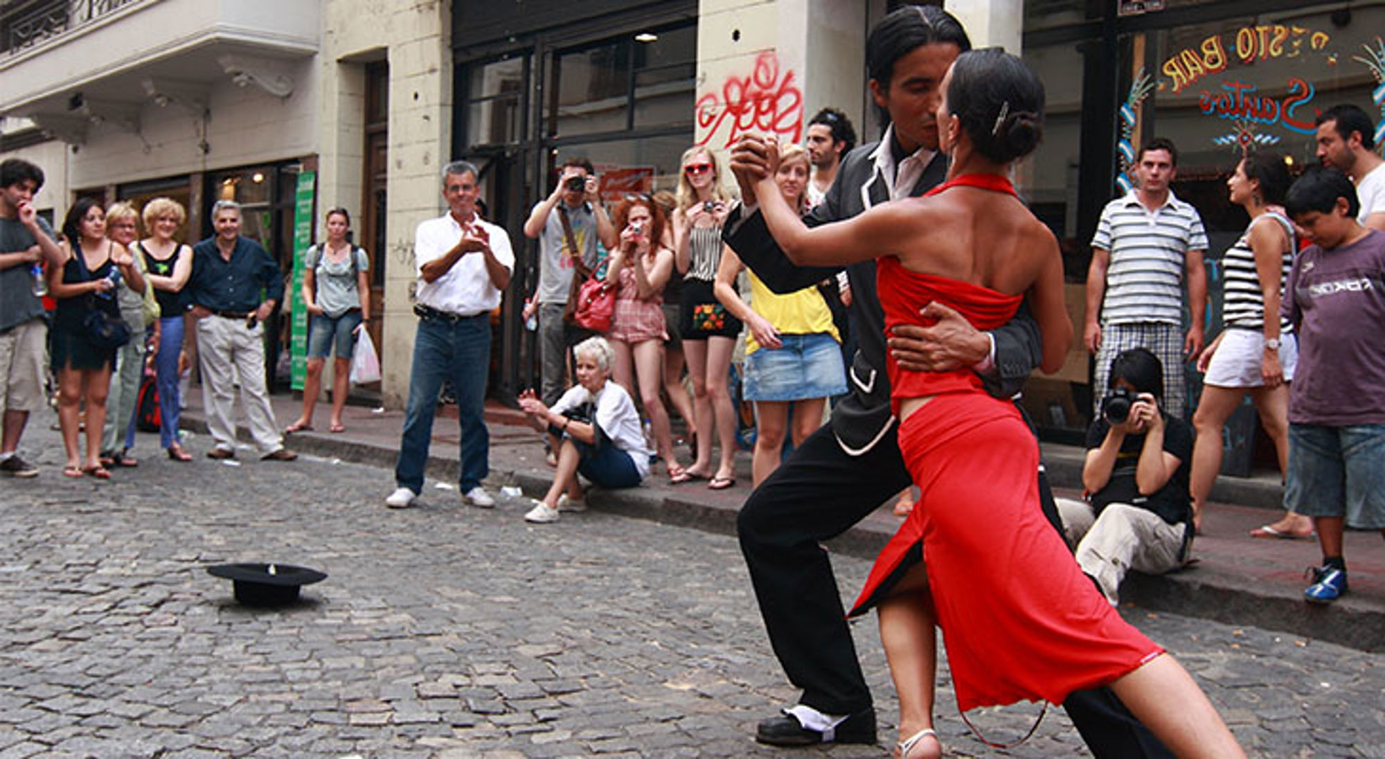 Tango danspaar danst op straat in Buenos Aires, Argentinië, met toeschouwers op de achtergrond.
