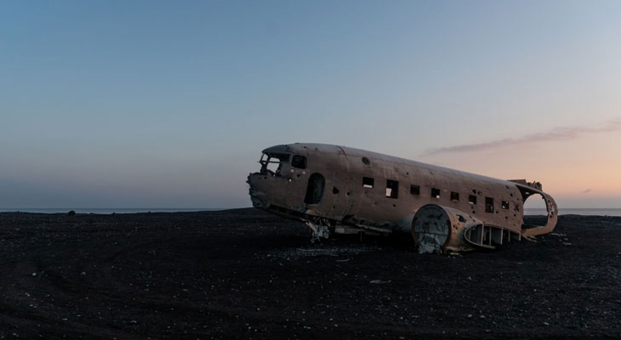 Vliegtuigwrak op het zwarte zandstrand Sólheimasandur in IJsland bij zonsondergang.