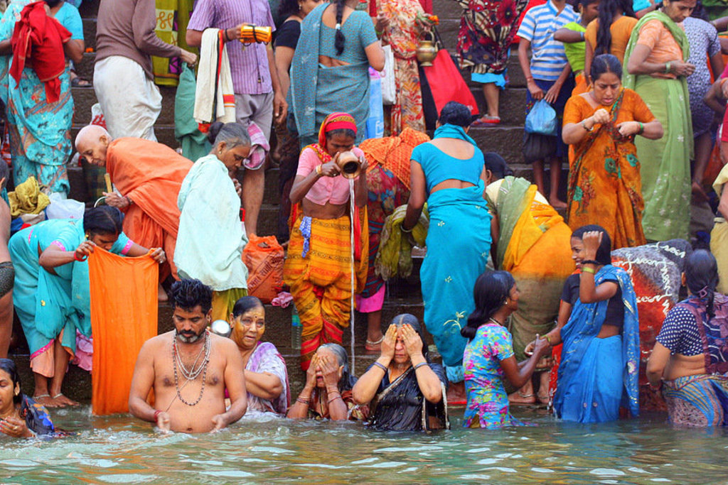 Pelgrims baden en wassen kleding bij een riviertrap in India tijdens de 22-35ers reis.