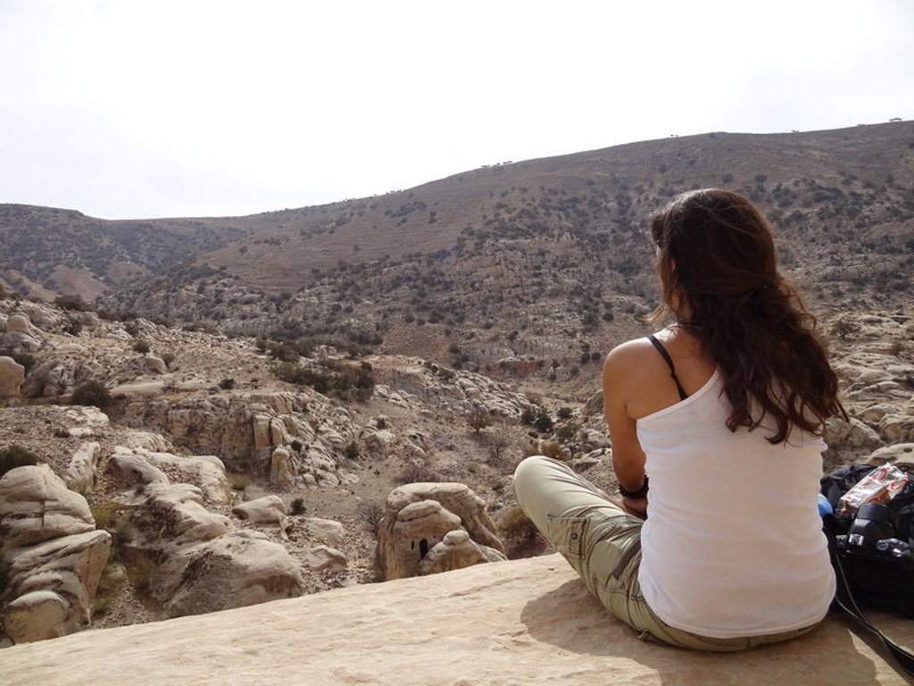 Jonge reiziger geniet van het uitzicht over de rotsachtige woestijn in Jordanië tijdens een 22-35ers groepsrondreis.