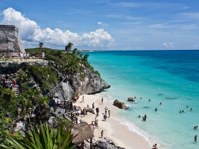 Maya-ruïnes van Tulum op een klif boven een wit zandstrand en turquoise zee in Mexico.