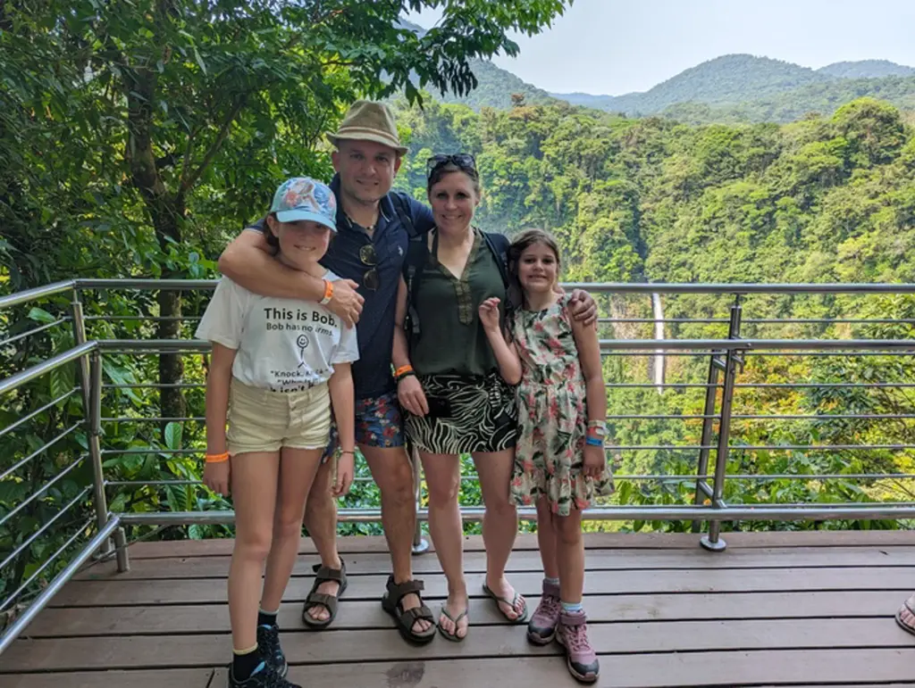 Gezin op uitkijkplatform met uitzicht op groen regenwoud en bergen tijdens familiereis Costa Rica.