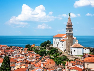 Uitzicht op de kustplaats Piran in Slovenië met de Sint-Joriskathedraal en rode daken aan de Adriatische Zee.