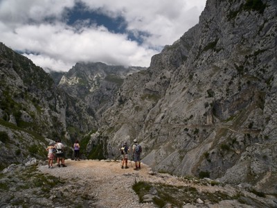 Wandelaars kijken uit over een bergkloof en rotswanden in de Picos de Europa, Spanje.