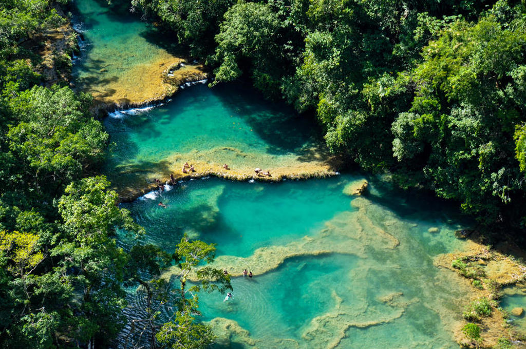 Turquoise waterpoelen in de jungle van Semuc Champey, Guatemala, met zwemmers.