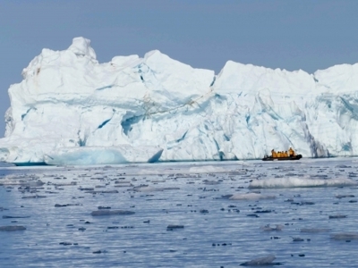 Zodiacboot vaart langs een enorme ijsberg in de wateren bij Spitsbergen.