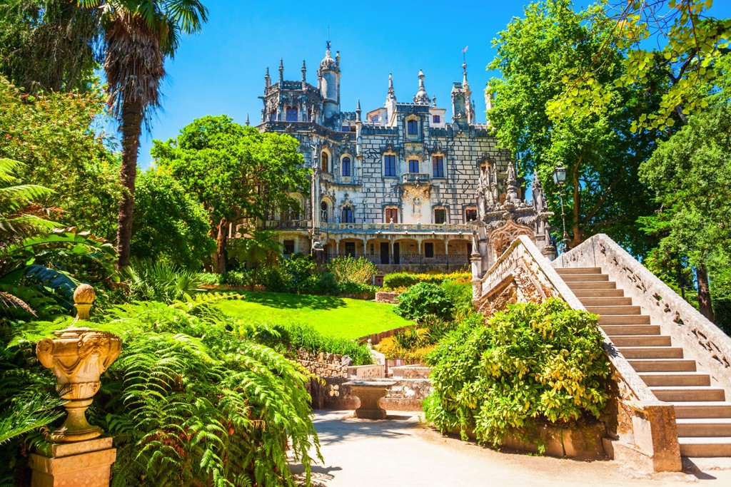 Paleis Quinta da Regaleira in Sintra, Portugal, met weelderige tuin en trap.