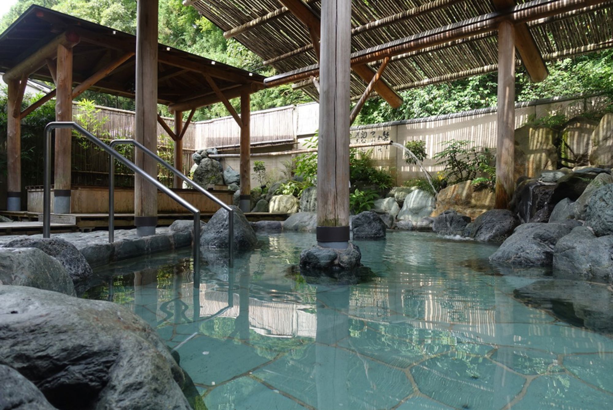 Buitenonsen in Japan met warm water, rotsen en houten overkappingen in een rustige spa-omgeving.