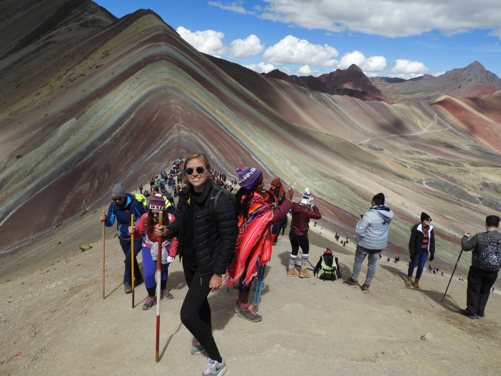 Wandelaars op de Rainbow Mountain (Vinicunca) in Peru tijdens een familiereis, met gekleurde bergkammen op de achtergrond.
