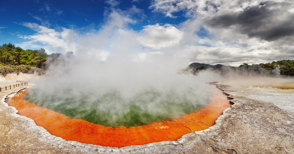 Stomende geothermische bron met feloranje rand in Rotorua, Nieuw-Zeeland, tijdens een groepsrondreis.