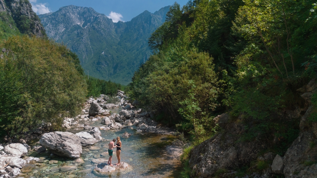 Gezin bij een heldere bergbeek in een groene vallei tijdens familiereis Albanië, Kosovo en Noord-Macedonië.