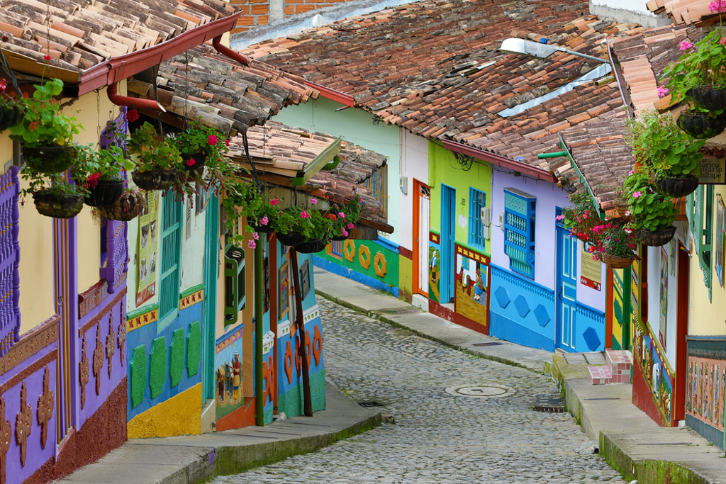 Kleurrijke straat met beschilderde huizen en hangende bloemen in Colombia tijdens een groepsrondreis.