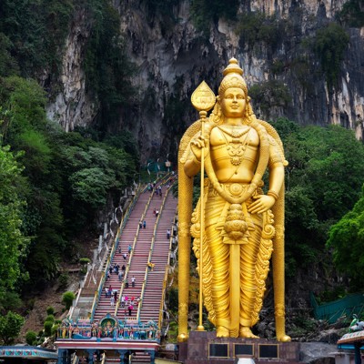 Gouden Murugan-beeld bij de Batu Caves met kleurrijke trap naar de grotten, Kuala Lumpur, Maleisië.