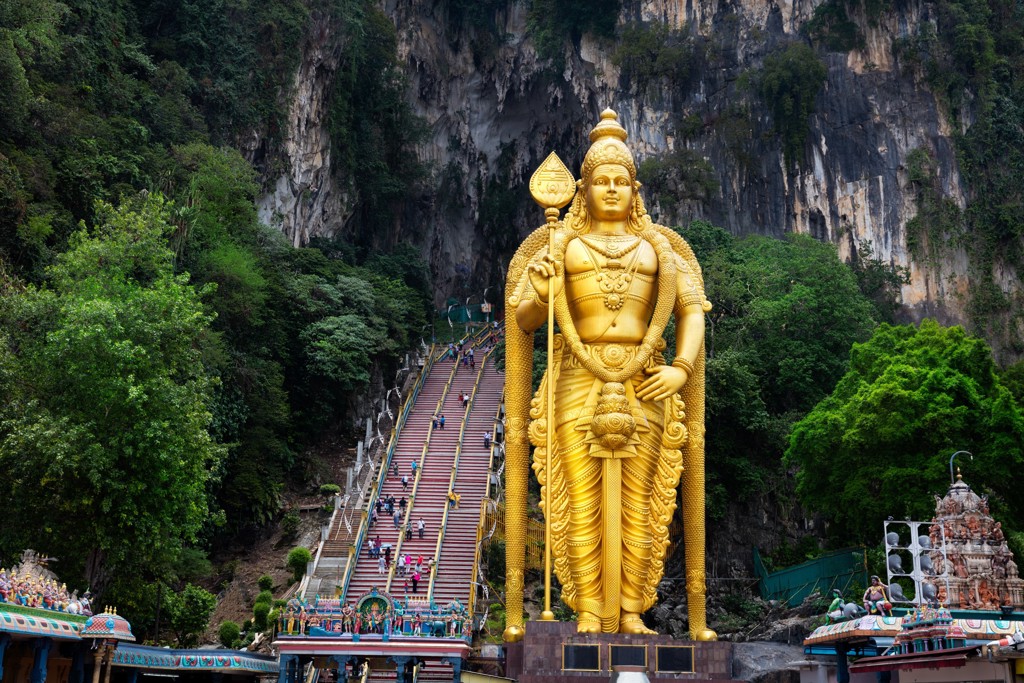 Gouden Murugan-beeld bij de Batu Caves met kleurrijke trap naar de grotten, Kuala Lumpur, Maleisië.