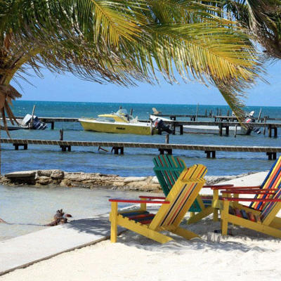 Kleurrijke strandstoelen onder palmbomen aan zee, met aanlegsteigers en bootjes langs de route Trans-Midden-Amerika.