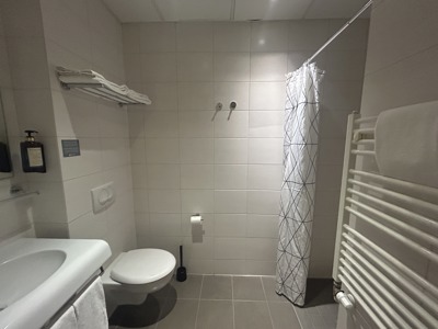 Badkamer van Hotel Klettur met douchegordijn, wastafel, toilet en handdoekenrek.