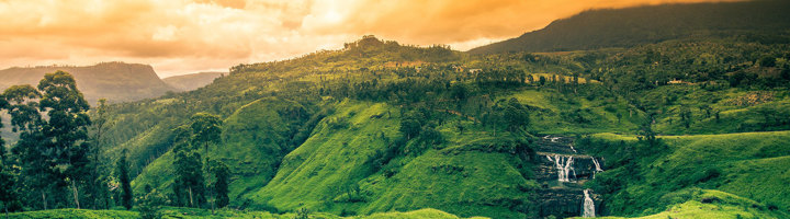Groene heuvels en waterval in de hooglanden van Sri Lanka bij zonsondergang.