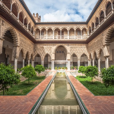 Binnenhof van het Alcázar in Sevilla met Moorse bogen, sierstucwerk, sinaasappelbomen en waterbassin.