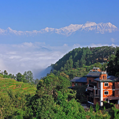 Groen heuvellandschap met dorp en uitzicht op de Himalaya tijdens groepsrondreis Noord-India en Nepal.