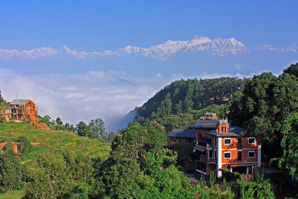 Groen heuvellandschap met dorp en uitzicht op de Himalaya tijdens groepsrondreis Noord-India en Nepal.