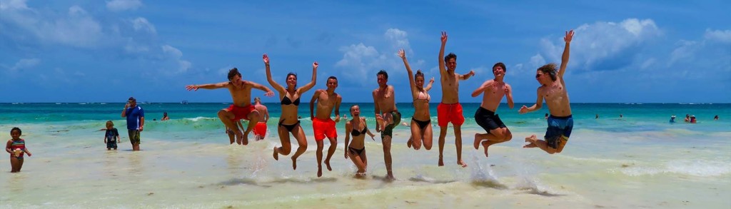 Vriendengroep springt in de zee op een strand in Mexico tijdens een familiereis.