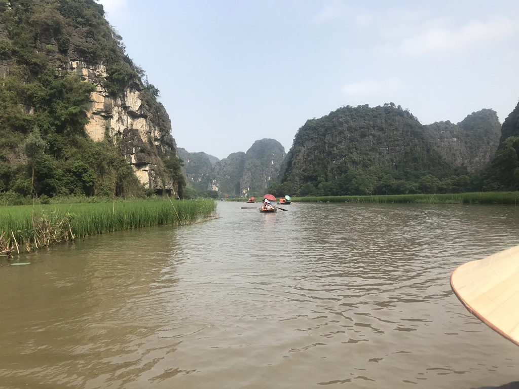 Boottocht over een rivier tussen kalkstenen rotsformaties tijdens een fietsvakantie in Vietnam.