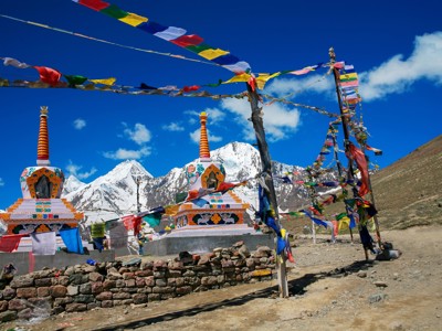 Boeddhistische stupa’s met gebedsvlaggen langs de route Spiti & Ladakh, met besneeuwde bergtoppen op de achtergrond.