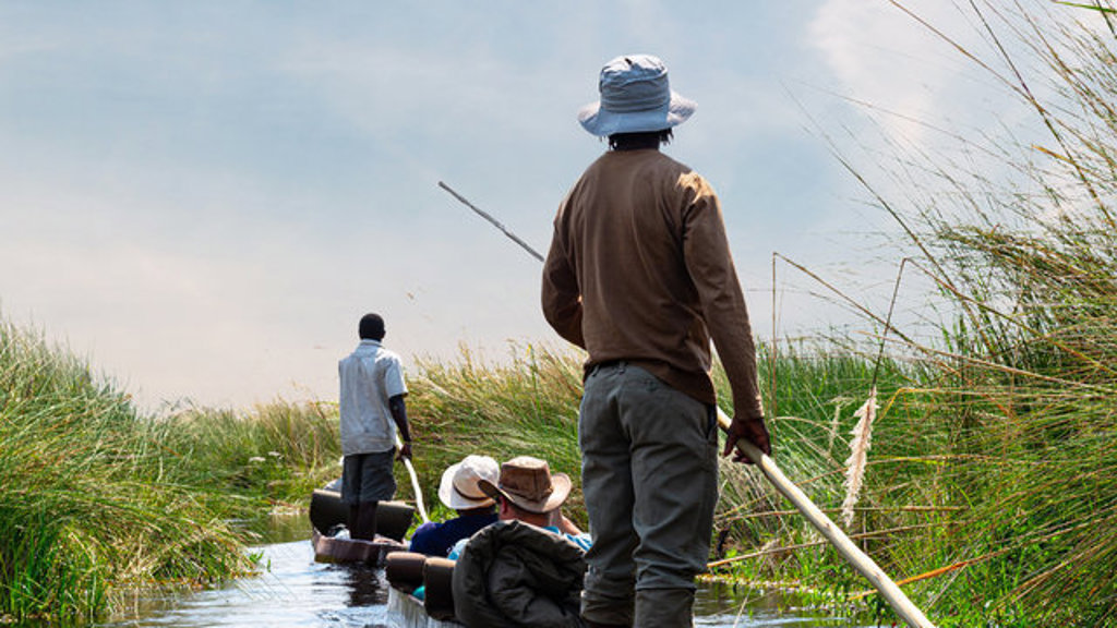 Mokorotocht met gids en reizigers door rietvelden in de Okavango Delta tijdens de 22-35ers reis Zuidelijk Afrika.