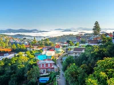 Uitzicht over Dalat in Vietnam met kleurrijke huizen, groene heuvels en ochtendmist in de vallei.