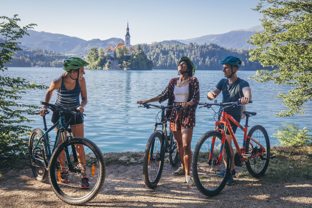Fietsers pauzeren bij het Meer van Bled met uitzicht op het eiland en de kerk, Slovenië.