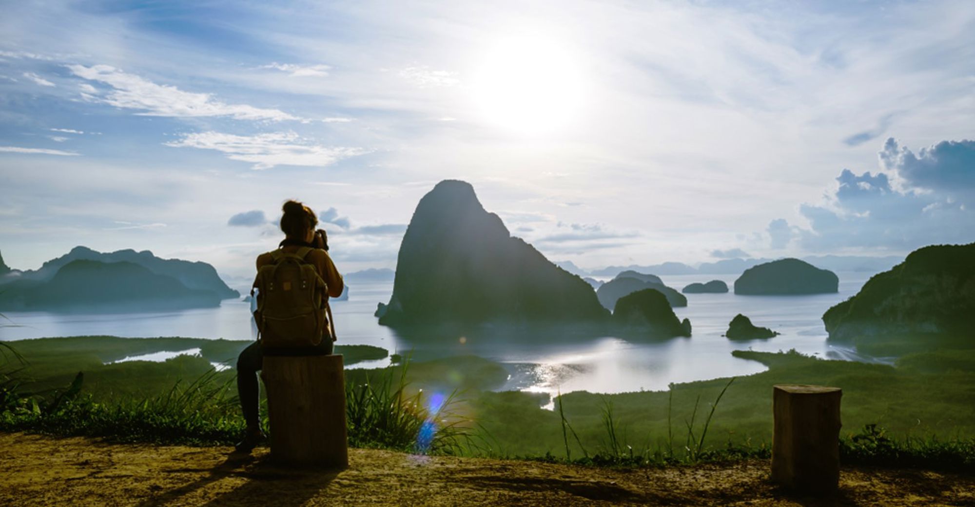 Uitzichtpunt over Phang Nga Bay met karstrotsen en eilanden, met een reiziger die de zonsondergang fotografeert.