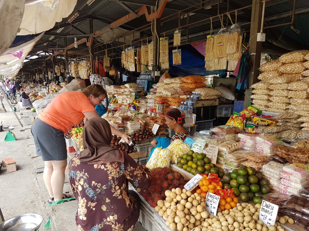Bezoeker koopt fruit en snacks bij een kraam op een lokale markt in Maleisisch Borneo.