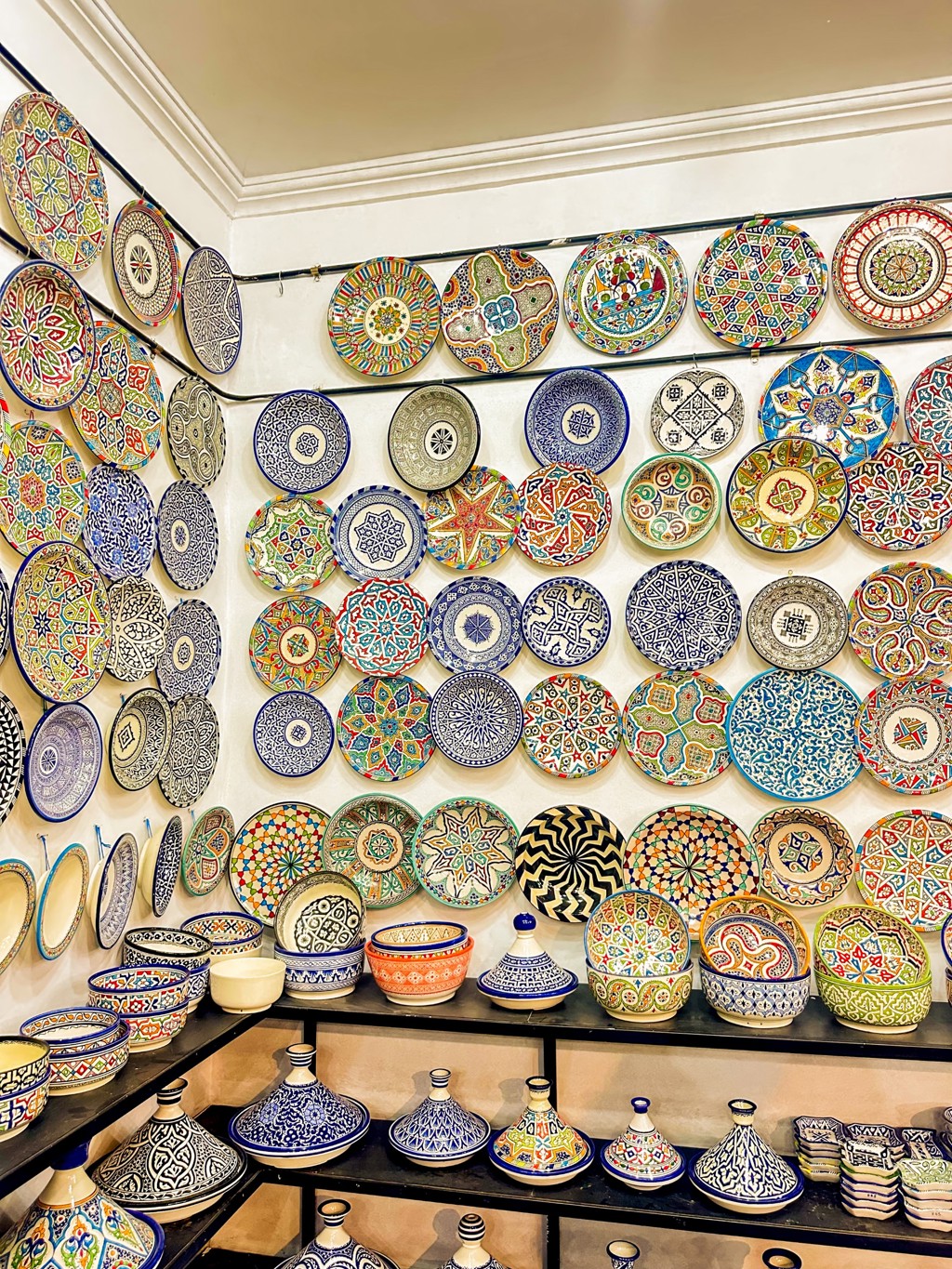 Kleurrijk Marokkaans aardewerk en tajines in een souk, hoogtepunt tijdens familiereis Marokko.