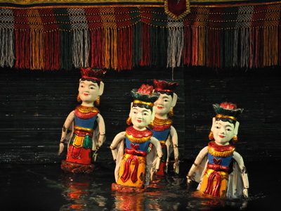 Waterpoppenspel in Vietnam met kleurrijke poppen op het water, onder een decor met franjes.