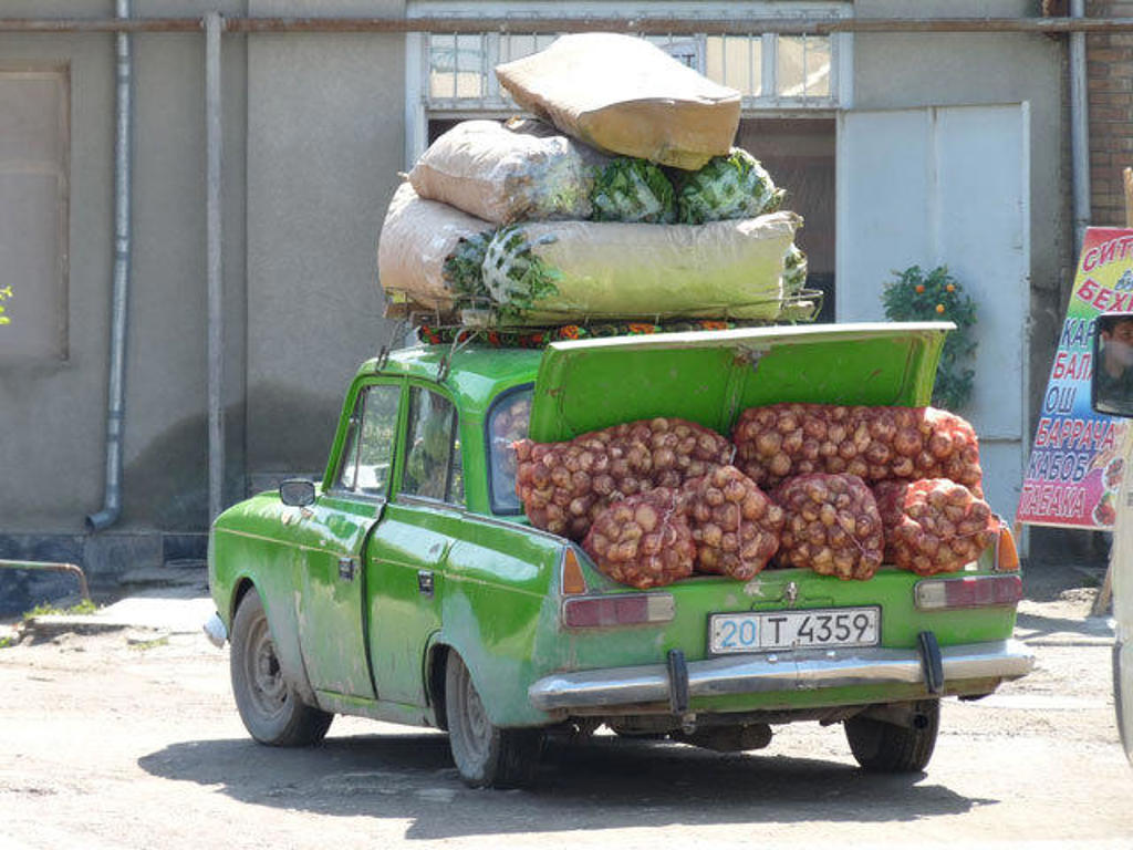Groene auto met zakken aardappelen en groenten op het dak in Oezbekistan, tijdens een groepsrondreis.