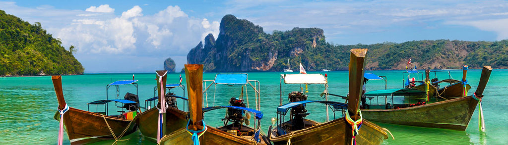 Longtailboten op turquoise zee bij kalkstenen eilanden in Thailand, Chill & Adventure rondreis.